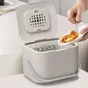 A person is adding food scraps to a Joseph Joseph Stack 4 compost bin in a kitchen. Voir les images du produit