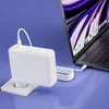 A white laptop charger plugged into a wall socket and connected to a laptop. Podgląd zdjęcia produktu