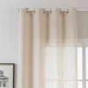 A close-up view of beige eyelet curtains hanging on a white curtain rod. Produktbild-Vorschau
