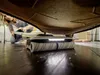 A woman is kneeling on the floor, cleaning under a piece of furniture with a Kärcher FC 7 Cordless Premium floor cleaner. Produktbild-Vorschau
