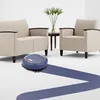 A blue robot vacuum cleaner is shown cleaning a floor in a living room setting with two beige armchairs and a small side table with a plant. Náhled obrázku produktu