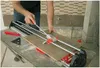 A person is using a tile cutter on a table. Podgląd zdjęcia produktu