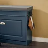 A close-up view of a blue shoe cabinet with a gray seat cushion and a brush hanging on the side. Náhľad obrázku produktu