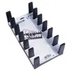 A black plastic lid holder with multiple slots, displayed on its packaging. Produktbild-Vorschau