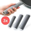 A hand holding a pan handle with a silicone grip, and three silicone grips laid out in front. Anteprima dell’immagine prodotto