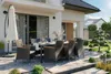 An outdoor patio set with a table and chairs, next to a modern house. Náhled obrázku produktu