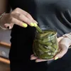 A person is holding a jar of pickles and taking one out. Anteprima dell’immagine prodotto