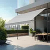 An outdoor patio with a retractable awning, dining table, and chairs, overlooking a city skyline. Produktbild-Vorschau