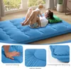 A woman and a baby are lying on a blue floor mattress in a bright room. Produktbild-Vorschau
