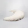 A cream-colored crescent-shaped pillow is shown against a white background. Produktbild-Vorschau