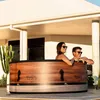 A couple relaxing in a portable hot tub on a patio.