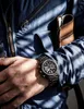 A close-up shot of a person wearing a watch and holding a wallet. Anteprima dell’immagine prodotto