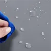 A hand holding a blue microfiber cloth wiping water droplets off a gray surface. Podgląd zdjęcia produktu
