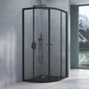 A modern bathroom with a black framed shower enclosure against a concrete wall, with a window showing a mountain landscape. Produktbild-Vorschau