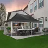A black canopy tent set up on a patio with a dining table and chairs underneath, next to a house and a grassy lawn. Podgląd zdjęcia produktu