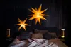 A bedroom scene with two star-shaped lamps illuminating the space above a bed. Produktbild-Vorschau
