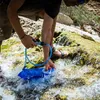 A person is filling a water bladder from a stream using a water filter. Anteprima dell’immagine prodotto