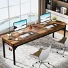 A long wooden desk with two computer setups, positioned in front of a large window with a scenic view. Two office chairs are placed near the desk. Podgląd zdjęcia produktu