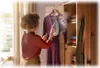 A person is ironing a purple dress with a steamer iron in front of a wardrobe. Voir les images du produit