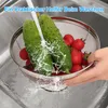 Cucumbers and tomatoes are being washed in a colander in a kitchen sink. Produktbild-Vorschau