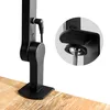 A close-up view of a black desk lamp clamp mechanism attached to a wooden surface, with a magnified inset showing the clamp detail. Náhled obrázku produktu
