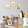 A child's room with framed pictures on the wall, toys, and stuffed animals. Produktbild-Vorschau