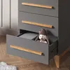 A close-up of a gray dresser with wooden handles, one drawer is partially open revealing a stuffed bunny. Náhled obrázku produktu