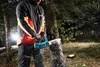 A person is using a cordless chainsaw to cut a log in a forest. Náhled obrázku produktu