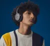 A young man wearing headphones and a striped sweater against a blue background. Produktbild-Vorschau