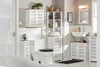 A well-lit bathroom with white tiled walls and floor, featuring various white bathroom storage cabinets with natural wood accents. Náhled obrázku produktu