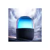 A close-up shot of a black Bluetooth speaker with a glowing blue and pink light on top, set against a dramatic cloudy sky background. Náhled obrázku produktu