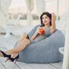 A woman sits in a bean bag chair on a wooden deck, holding a drink. Náhľad obrázku produktu
