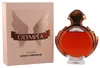 Paco Rabanne Olympéa Intense Eau de Parfum mit rundem, bronzefarbenem Flakon neben zartrosafarbener Verpackung mit Flügelmotiv. Produktbild-Vorschau