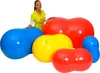 A woman stands behind several colorful peanut-shaped exercise balls. Produktbild-Vorschau