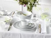 A table setting with white porcelain dinnerware and gold cutlery, decorated with small white flowers. Produktbild-Vorschau