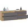 A modern dresser with four drawers, two on each side, with a wood-tone top and graphite gray drawer fronts. Two decorative vases and a stack of books with a black bottle are on top. Produktbild-Vorschau