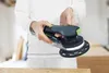 A person is holding a Festool Akku-Exzenterschleifer ETSC 2 150 4,0 I-Plus in a workshop setting. Voir les images du produit