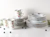 A collection of ceramic dishes and cups with a fruit motif, arranged on a white surface with a light gray background. Produktbild-Vorschau