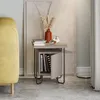 A modern nightstand next to a yellow sofa, with books and decor on top and inside. Produktbild-Vorschau