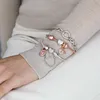 A person's arm wearing multiple Pandora charm bracelets. Anteprima dell’immagine prodotto