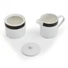 A white ceramic sugar bowl with a black and gold band, a matching creamer pitcher, and a lid are displayed on a white background. Podgląd zdjęcia produktu