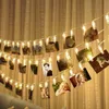A string of lights with photos clipped to it, hanging in front of a curtain. Produktbild-Vorschau