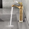A vintage-style brass faucet with a ceramic handle is shown in a bathroom sink, with water running. Náhled obrázku produktu