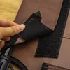 A hand is shown attaching a velcro strap to a brown fabric product, possibly a pet bed or cover. Produktbild-Vorschau