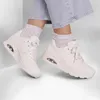 A pair of beige Skechers Uno sneakers worn by a person with light blue jeans and grey socks. Voir les images du produit