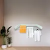 A wall-mounted drying rack with towels and a t-shirt hanging on it, next to a potted plant. Produktbild-Vorschau