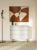 A modern white dresser with abstract art above it and a floor lamp. Voir les images du produit