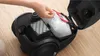 A person is replacing a filter bag in a black vacuum cleaner. Produktbild-Vorschau