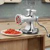 A manual meat grinder is shown on a wooden countertop with chopped red peppers next to it. Podgląd zdjęcia produktu
