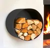 A black, circular, wall-mounted firewood rack filled with logs, next to a fireplace with flames. Produktbild-Vorschau